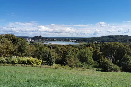 Uitzicht op een groen landschap met een meer en een kasteel in de verte