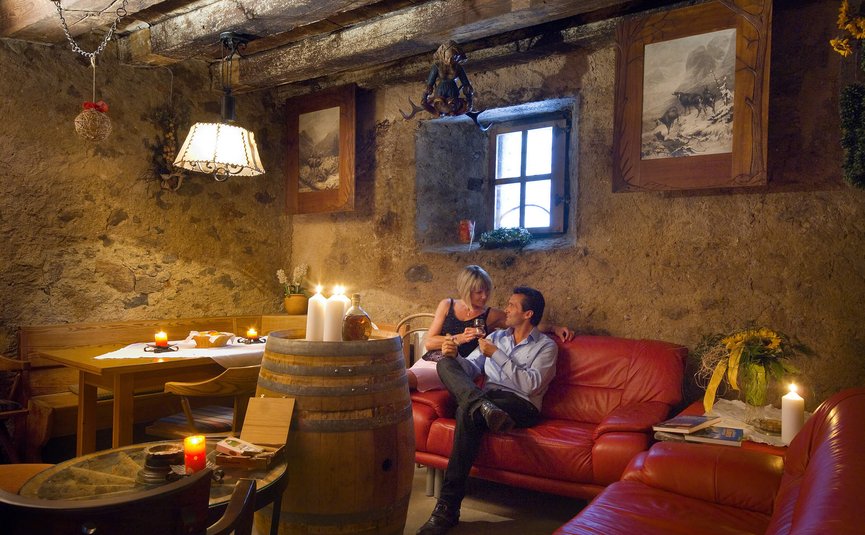 Paar genießt ein Getränk in rustikalem Wohnzimmer mit Kerzenlicht