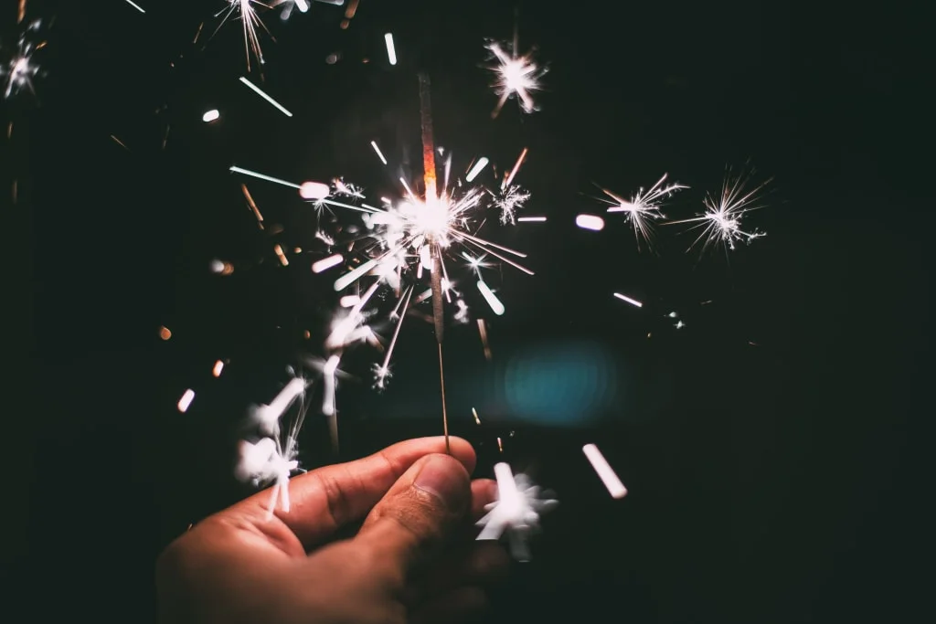SILVESTER im Mühlviertel 2026/27 Hand die een brandende sterretje in het donker vasthoudt