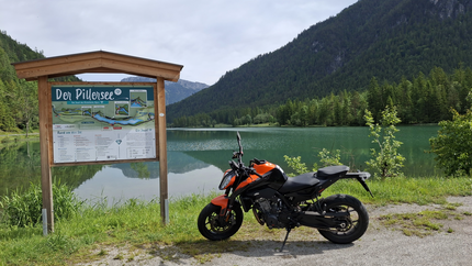 Pillerseetour Motorrad neben einem See mit Wanderkarte und Bergen im Hintergrund