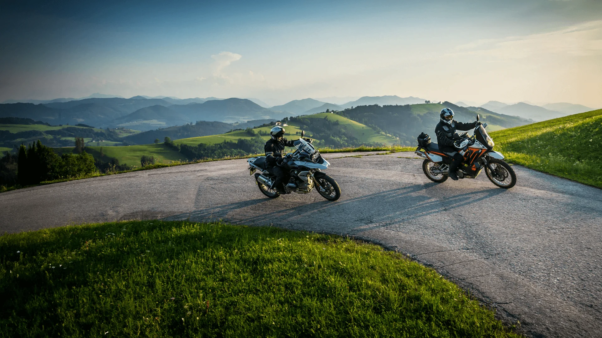 Two motorcyclists on winding mountain road in sunny weather