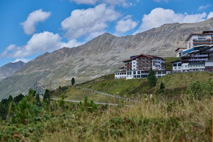 Alpenhotel Laurin © studio22.at - Marcel Hagen Alpenhotel am Hang mit Bergpanorama unter blauem Himmel