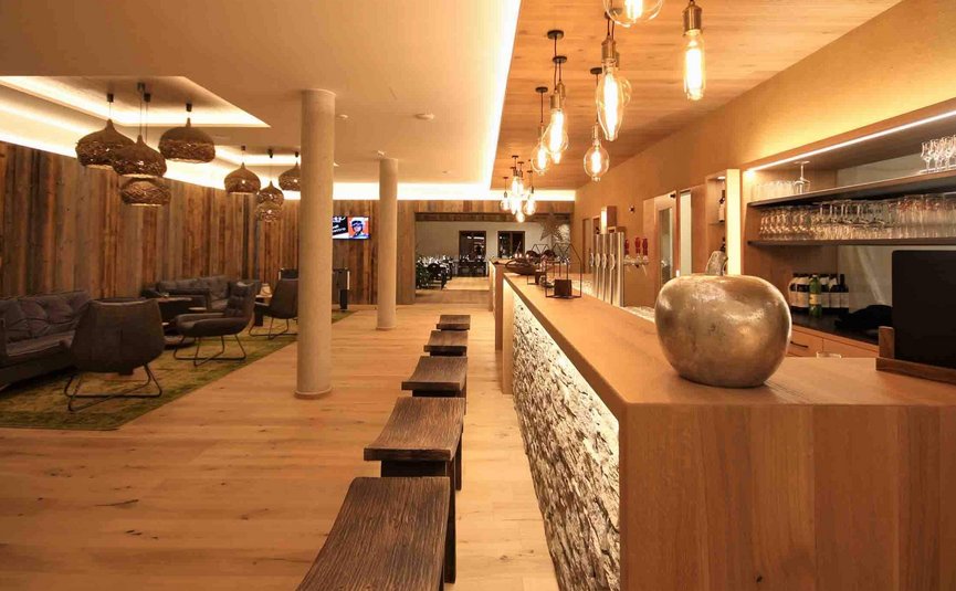Moderner Barbereich mit Holztheke, Barhockern und gemütlicher Lounge