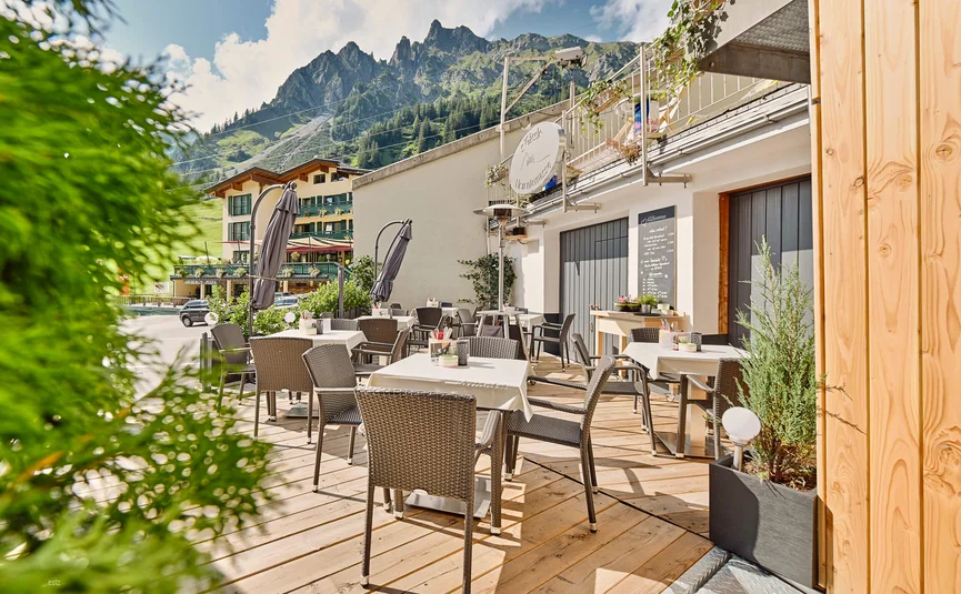 Outdoor café seating with tables, chairs and mountain view on a sunny day