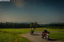 Mühlviertel ..the bear round Two motorcycles riding on a rural road through green fields under clear sky