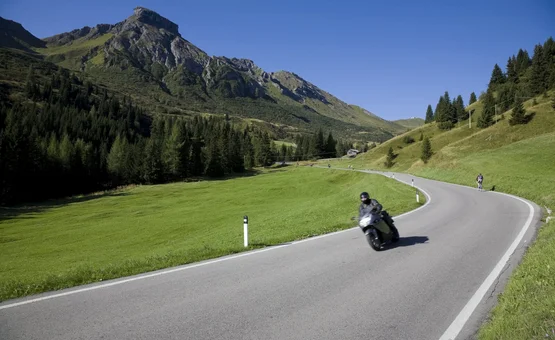 Motorradurlaub in Valsugana – Kaiserjägerstraße © Energy Hotel Motorradfahrer auf kurviger Bergstraße mit grünen Wiesen und Bergen im Hintergrund