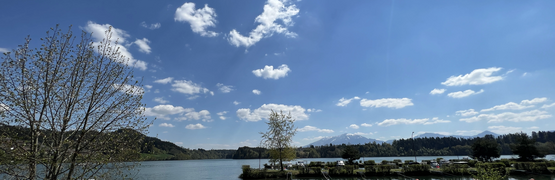 Bootshafen an einem See mit Bergen und blauem Himmel