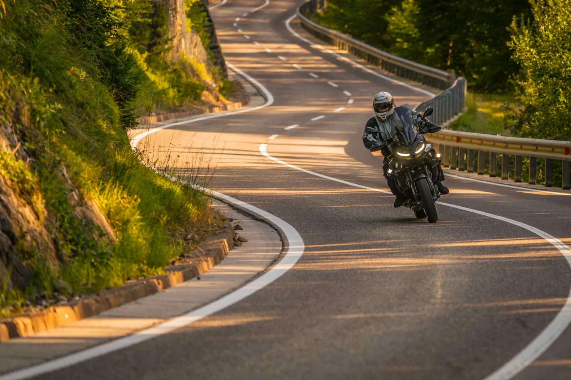 Motorcyclist riding on winding country road in sunny landscape