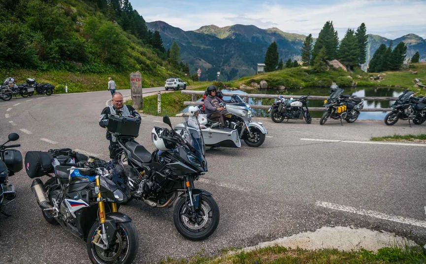 Motorradfahrer machen Pause auf Bergstraße mit Bergen und See im Hintergrund