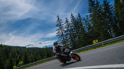 Königstour Tour 8 Motorradfahrer fährt kurvige Straße am Waldrand bei blauem Himmel