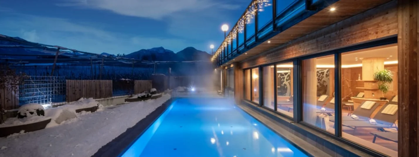 Winter Wellness Weekend 3 Nights Heated outdoor pool beside modern building with snow and mountain view at dusk