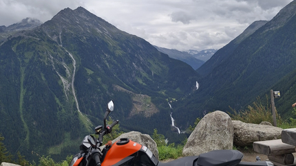 Gerlosrunde Tour 3 Oranges Motorrad vor Bergen und bewölktem Himmel