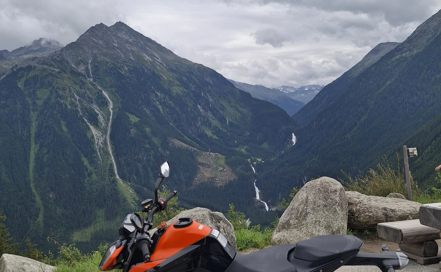Oranges Motorrad vor Bergen und bewölktem Himmel