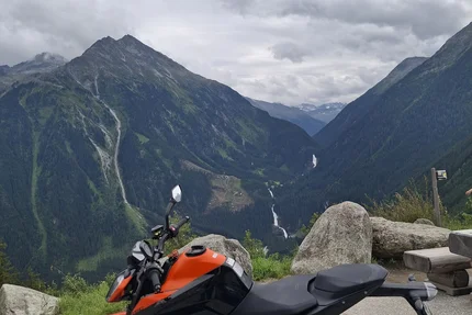 Orange motorcycle parked with mountain landscape and cloudy sky