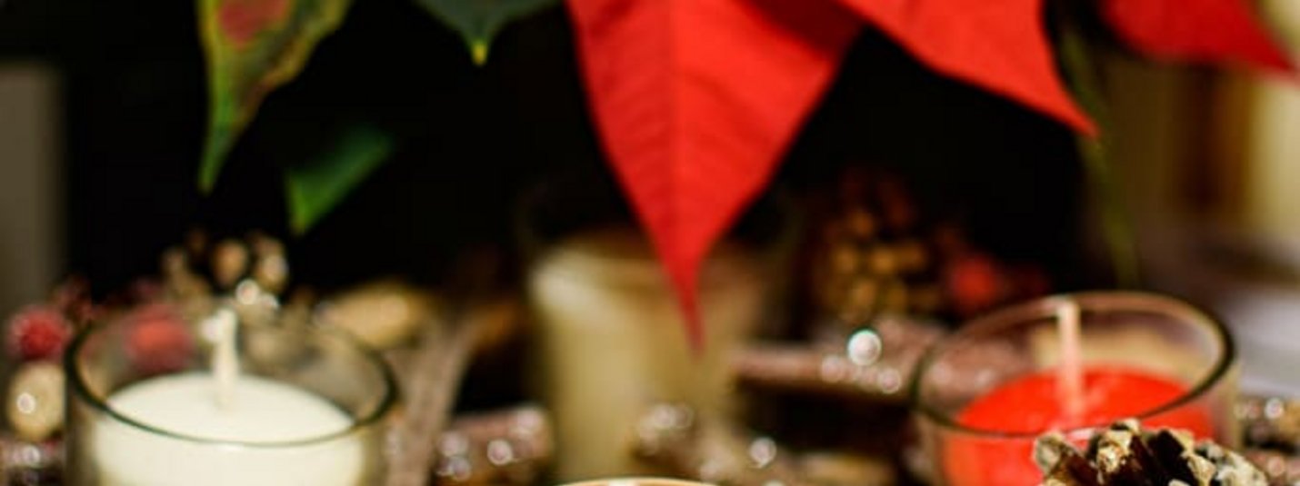 Weihnachtliche Kerzen und rote Weihnachtssternblätter mit Tannenzapfen