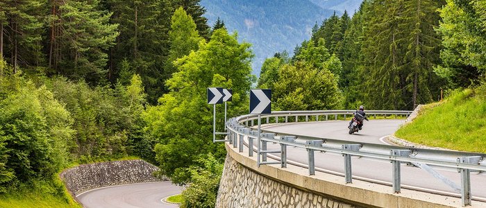 3 Zinnen – Kronplatz – Eisacktal © Alexander Seger Motorradfahrer fährt auf kurviger Bergstraße im Wald