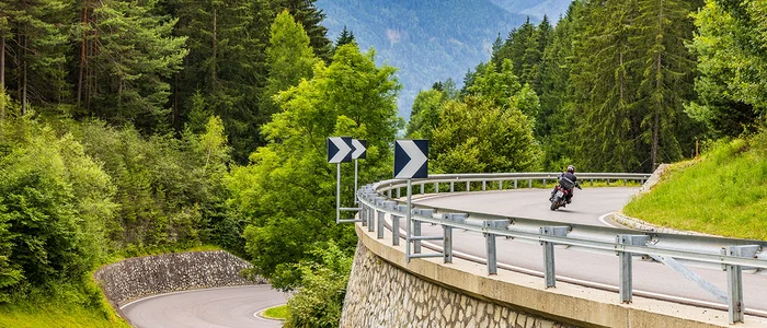 Motorcyclist riding on winding mountain road through forest