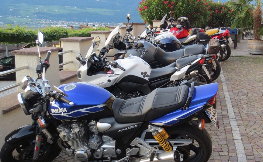 Motorräder in einer Reihe auf gepflastertem Weg mit Bergblick