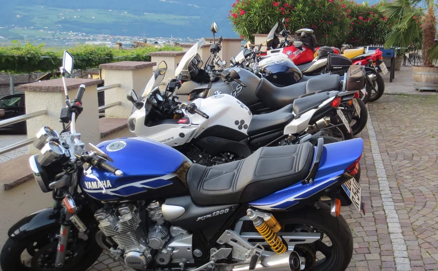 Motorcycles lined up on cobblestone path with mountain view