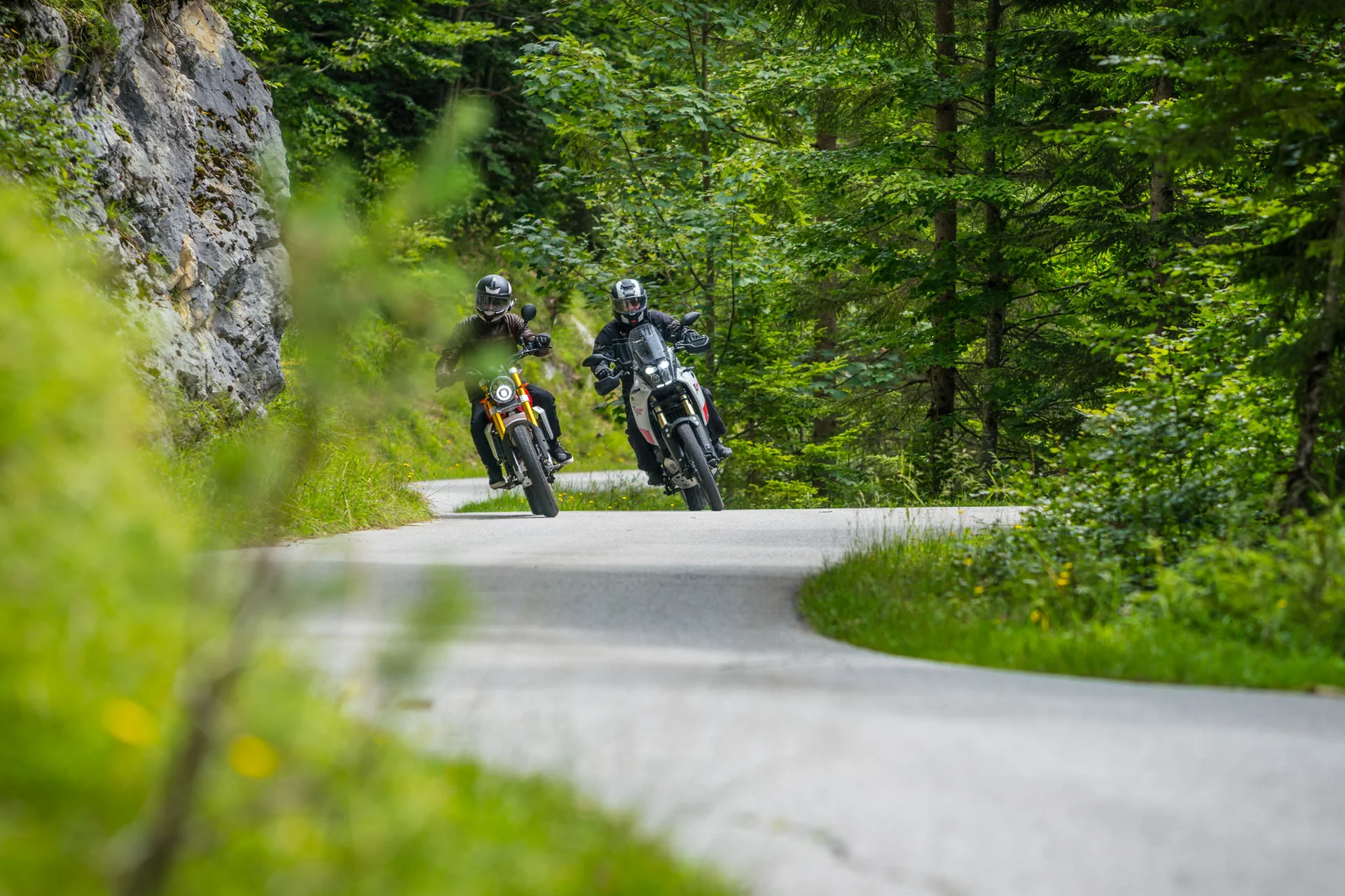 Motorradurlaub © Moppetfoto.de Zwei Motorradfahrer fahren auf kurviger Straße durch grünen Wald