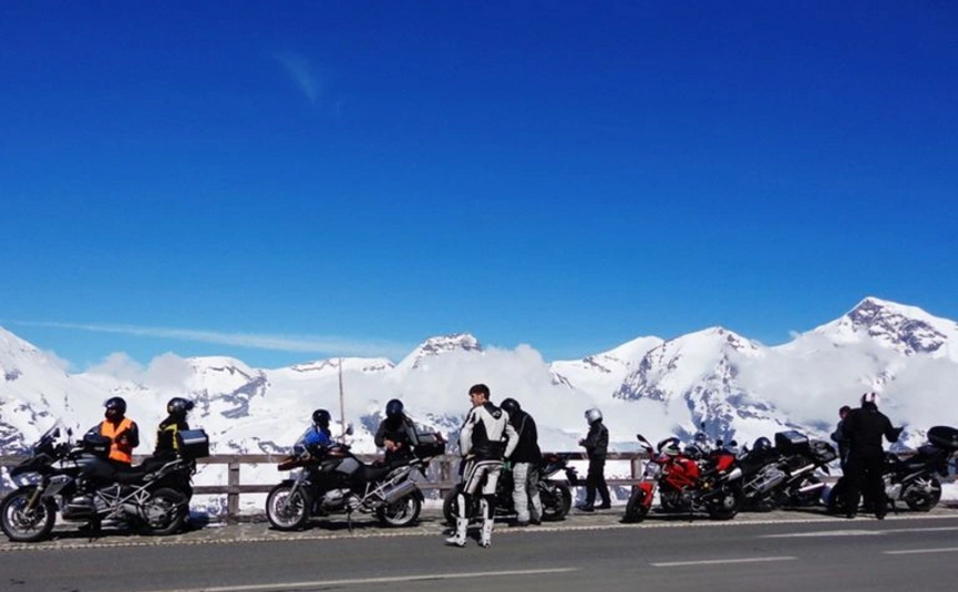 Motorradfahrer mit Motorrädern an Bergstraße mit schneebedeckten Gipfeln