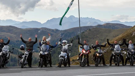 Geschichte der MoHo's Motorradgruppe posiert auf Bergstraße mit Alpen im Hintergrund