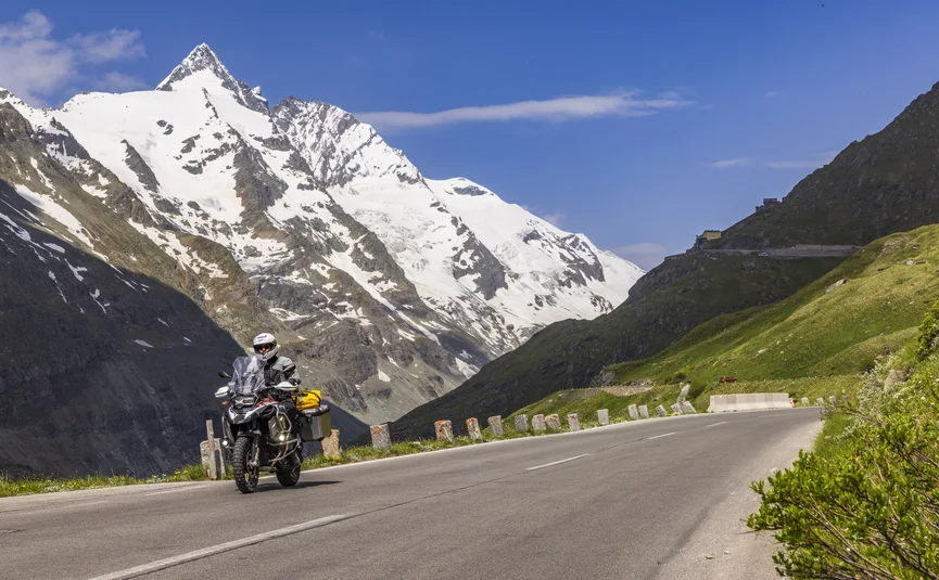 Motorcyclist riding on mountain road with snowy peak in the background