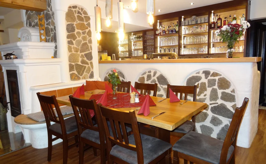 Cozy dining area with wooden table, chairs and rustic stone wall background