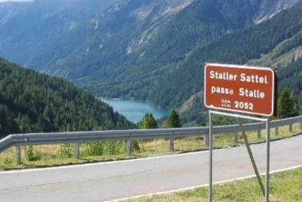 Road sign Staller Sattel pass at 2052 meters with mountain lake view