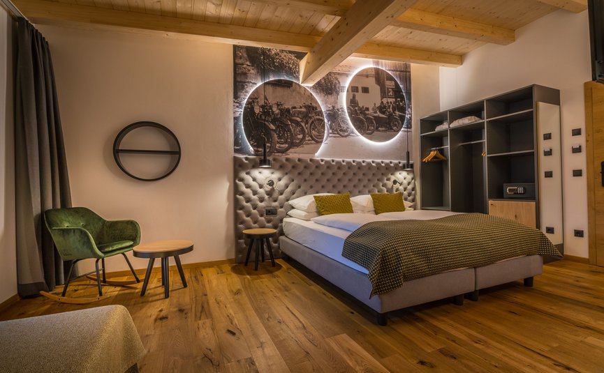 Modernes Hotelzimmer mit Holzboden, Doppelbett und Vintage-Motorradbild