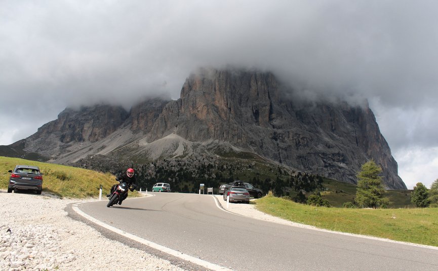 Motorradfahrer auf Bergstraße mit nebelverhülltem Felsen im Hintergrund