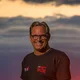 Man in black t-shirt smiling with red sunset in the background