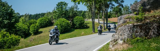 Motorvakantie in het Mühlviertel © Moppetfoto.de Motorrijders op een landelijke weg met bomen en rotsen