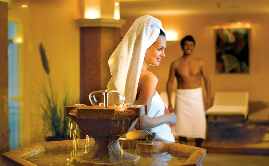Woman and man in towels in a spa room with a water fountain