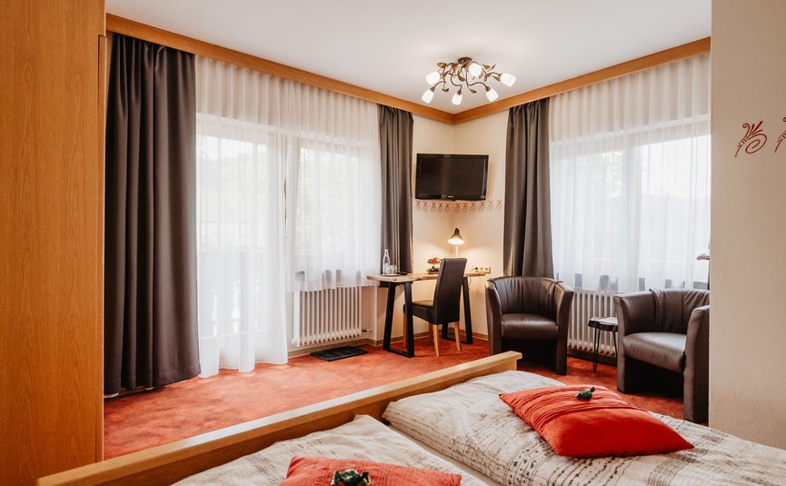 Gemütliches Hotelzimmer mit zwei Betten, Arbeitsplatz und Sitzbereich