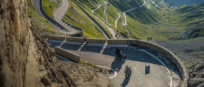 Reschensee – Stilfserjoch – Vinschgau © Moppetfoto.de Motorräder fahren auf einer kurvigen Gebirgsstraße mit steilen Wänden