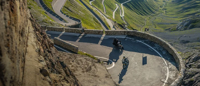 Motorcycles riding on a winding mountain road with steep slopes