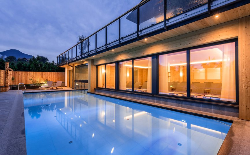 Modernes Haus mit beleuchtetem Pool bei Abenddämmerung