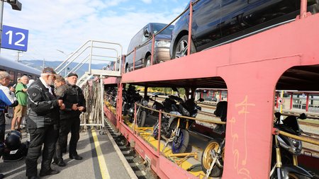 Motorrad- und Autoreisezug © Eduard Bopp Personen am Bahnsteig neben Zug mit transportierten Motorrädern und Autos