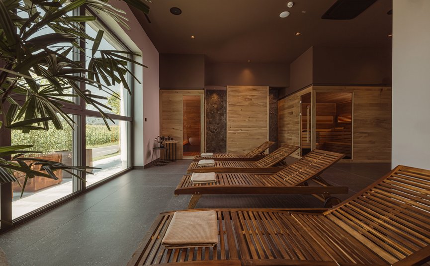 Ruheraum mit Holzliegen und Sauna in modernem Wellnessbereich