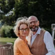 Christine Engl & Josef Moser © Niko Opetnik Älteres Paar umarmt sich im Garten mit Bäumen im Hintergrund