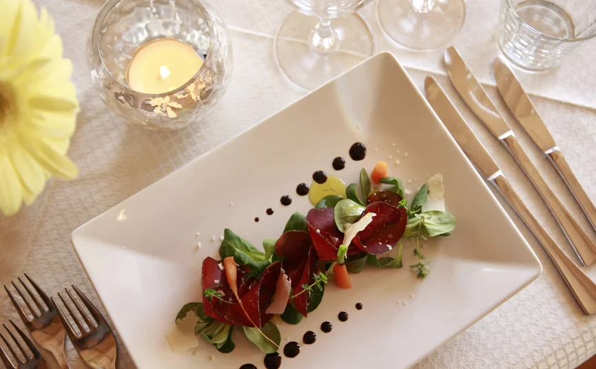 Gourmet salad with arugula and balsamic dressing on a white plate
