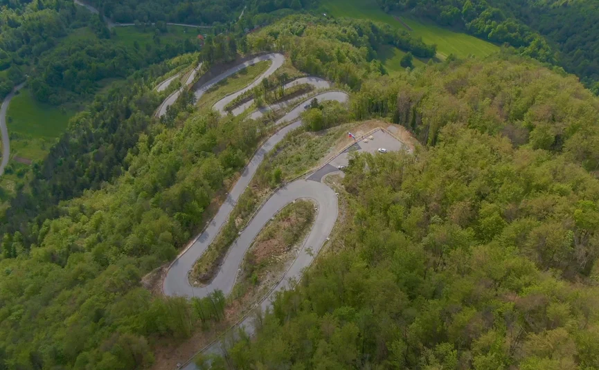 Serpentinenstraße durch grünen Wald auf einem Berg aus der Vogelperspektive