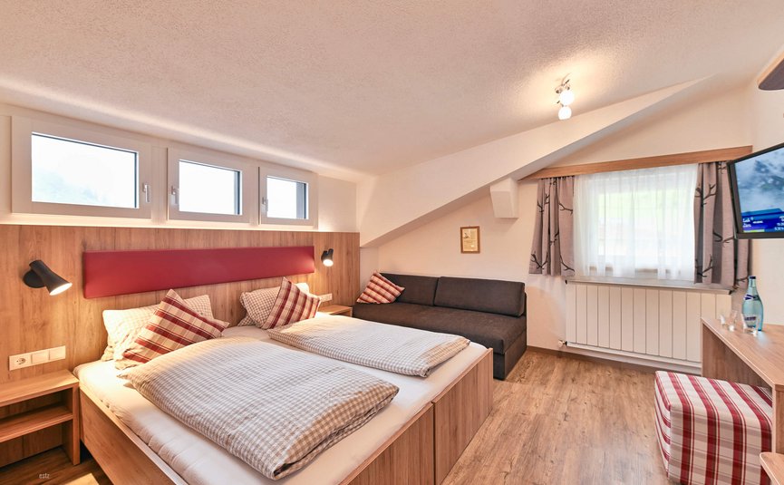 Haus Flexen © Mathies Wilhelm Robert jun. Gemütliches Hotelzimmer mit Doppelbett und Couch unter Dachschräge