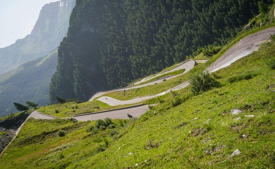 Serpentinenstraße zwischen grünen Bergen unter klarem Himmel