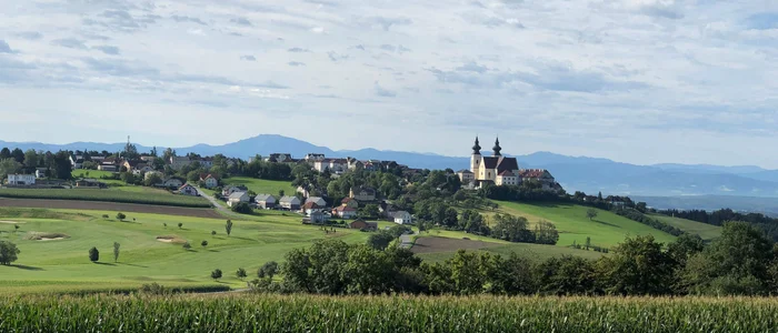 Hotel Rose **** © Hotel Rose Blick auf Dorf und Kirche auf grünem Hügel unter bewölktem Himmel