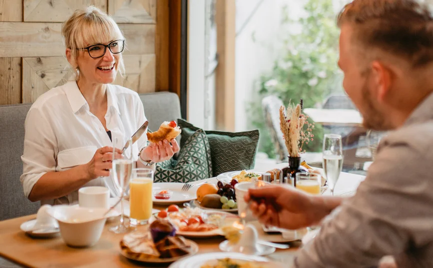 Woman and man having breakfast and talking at cozy dining table