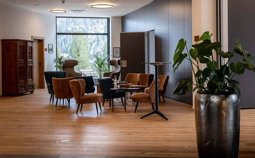 Gemütliche Lounge mit Stühlen, Tischen und Pflanzen vor großem Fenster
