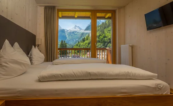 30 Jahre Jubiläums Bike Wochen Schlafzimmer mit Doppelbett und Bergblick durch Balkontür