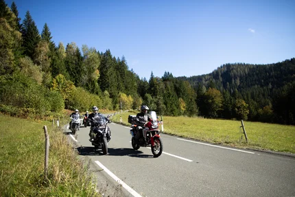 Motorrijders op landweg door groen landschap bij heldere lucht